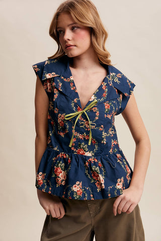 Woman wearing a floral peplum top with a beige background