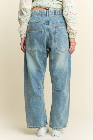 Person wearing light blue jeans on a beige background