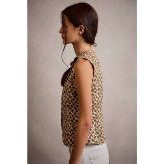 Woman wearing a sleeveless patterned top against a plain background