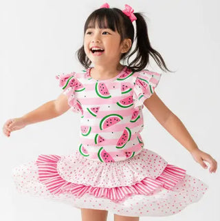 Child wearing a pink watermelon print dress with a white background