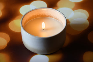 Candle in a white holder with a blurred bokeh background