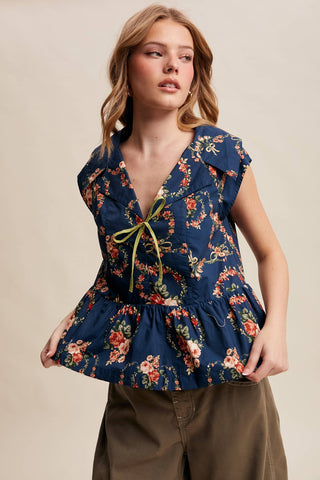 Woman wearing a floral peplum top against a beige background