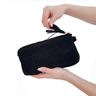 Black woven clutch bag with tassel held by a hand on a white background