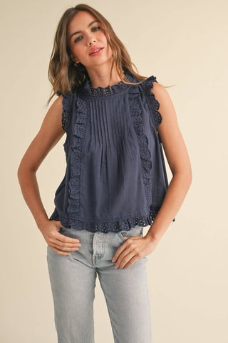 Blue sleeveless blouse with eyelet and ruffle trim.