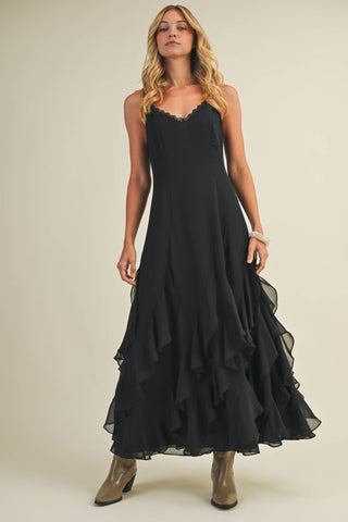 Woman wearing a black dress with ruffled layers on a plain background