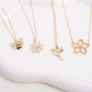 Set of gold necklaces with various charms on a white surface
