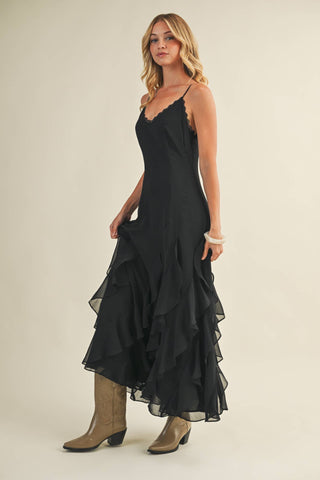 Woman wearing a black dress with ruffled layers on a plain background