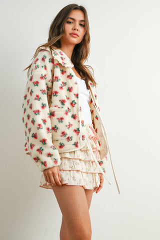 Woman wearing a floral blouse and shorts on a white background