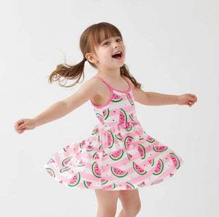 Child wearing a pink watermelon patterned dress on a white background