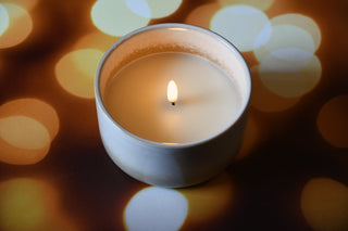 Candle in a tin container with a blurred bokeh background