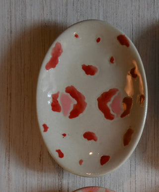 Small ceramic dish with red floral patterns on a wooden surface