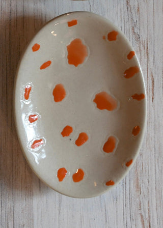 Ceramic plate with orange speckles on a wooden surface
