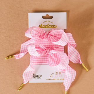 Pink checkered shoe laces with gold tips on a beige background