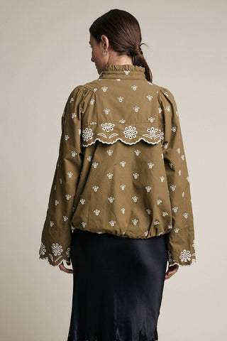 Woman wearing a brown blouse with white floral patterns on a beige background