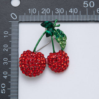 Decorative cherries with red gemstones on a white background with a ruler for scale.