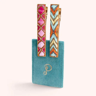 Colorful earrings with geometric design on a turquoise stand against a white background