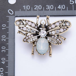 Decorative bee-shaped brooch with gemstones on a ruler for scale
