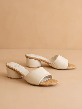 Pair of white sandals with cork sole on a beige background