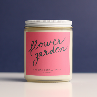 Candle jar with a pink label reading 'flower garden' on a dark background
