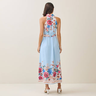 Woman wearing a floral dress with a light blue base on a plain background