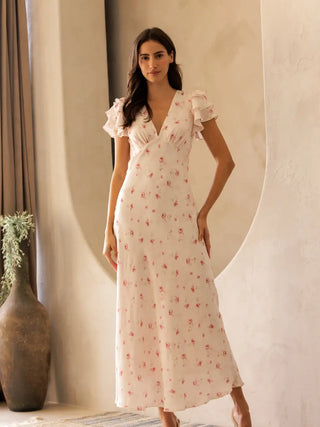 Woman wearing a floral dress standing in a room with a neutral background