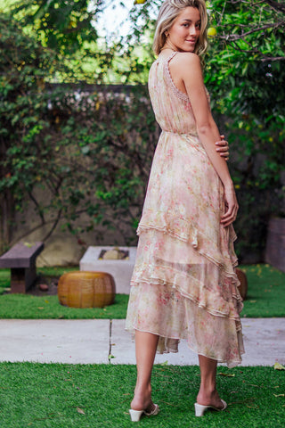 Woman wearing a floral dress standing outdoors with greenery in the background