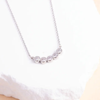 Silver necklace with small round stones on a white background