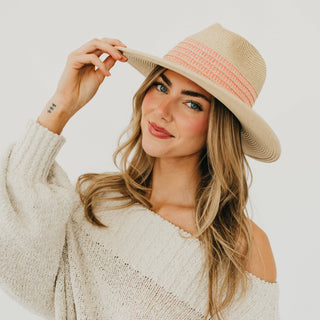 Woman wearing a beige hat with pink band against a white background