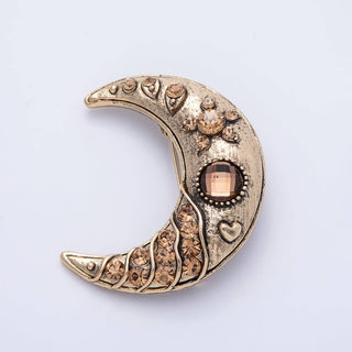 Decorative crescent moon brooch with brown gemstones on a light gray background