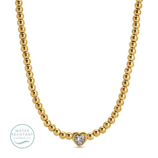 Gold beaded necklace with a heart-shaped clasp on a white background