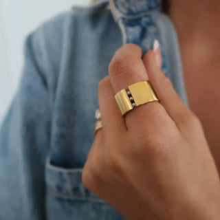 Gold ring on a finger with a blurred denim background