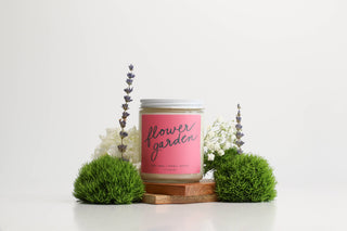 Candle labeled 'flower garden' with decorative plants on a white background