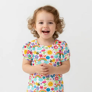 Child wearing a colorful shirt with cartoon designs on a white background