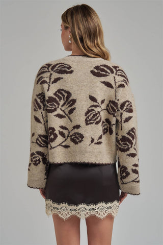Woman wearing a floral-patterned cardigan on a gray background