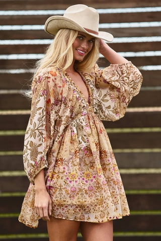 Woman wearing a floral dress and cowboy hat against a wooden background