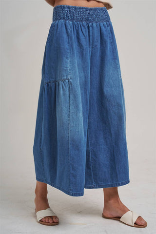 Blue denim skirt worn by a person on a plain background