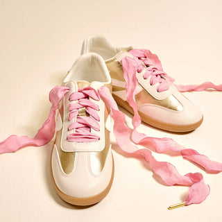 White sneakers with pink laces on a beige background