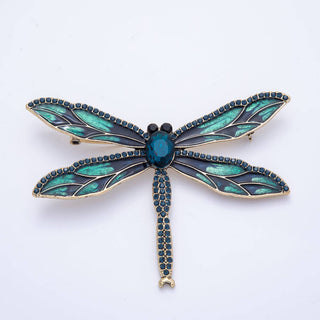 Dragonfly-shaped brooch with green and black details on a white background