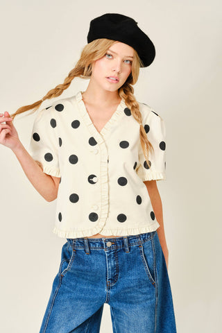 Woman wearing a polka dot blouse and black beret against a plain background