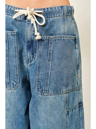 Close-up of blue denim shorts with a drawstring on a plain background