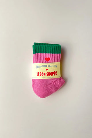 Pink and green sock with a label on a light gray background
