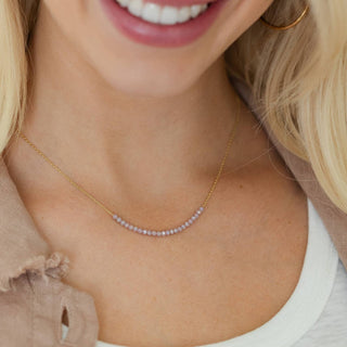 Close-up of a woman wearing a delicate necklace with small beads.