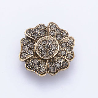 Decorative brooch with floral design and rhinestones on a white background