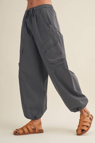 Dark gray cargo pants worn by a person on a beige background