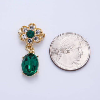 Gold brooch with green gemstones next to a quarter on a white background