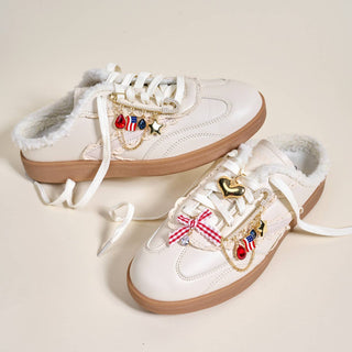 White sneakers with decorative charms on a beige background