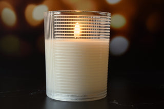 Candle in a ribbed glass holder with a blurred bokeh background