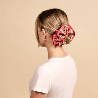 Person with a red patterned scrunchie in their hair against a beige background