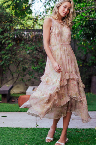 Woman wearing a floral dress standing outdoors with greenery in the background