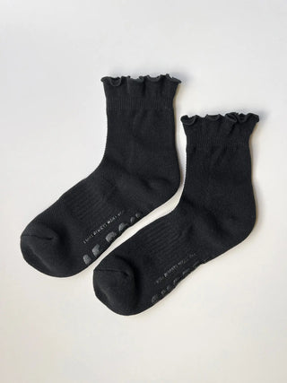 Pair of black socks with ruffled top on a light gray background